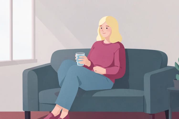 Persona relajada en un sofá con un vaso de agua, día de descanso.